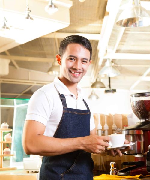 Coffeeshop - asian barista presents coffee in his shop